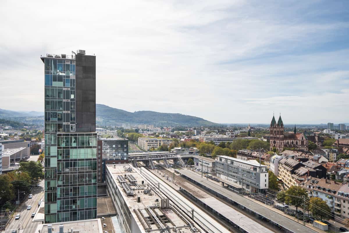 Turm der Bahnhofszeile Freiburg mit Gleisfeld und Stadtpanorama von oben