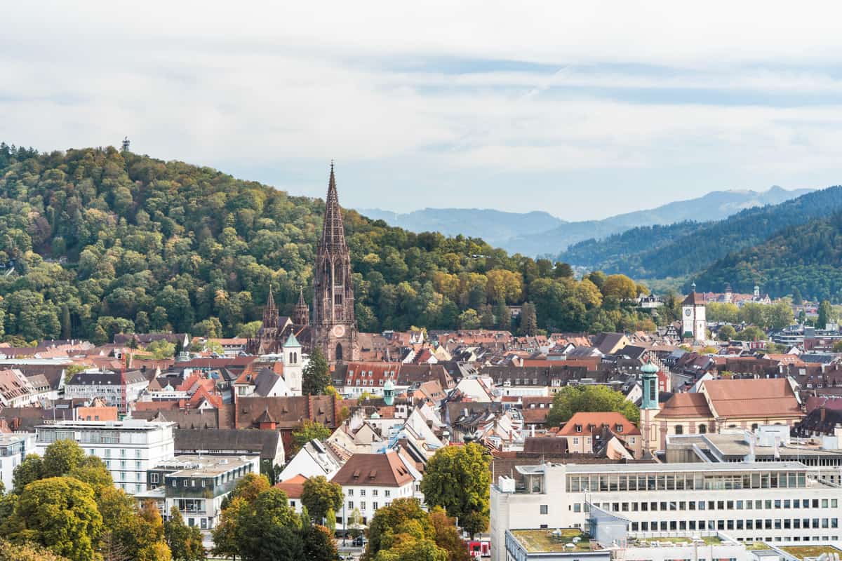 Blick über die Freiburger Altstadt mit Münster, bewaldeten Hängen und Schwarzwald