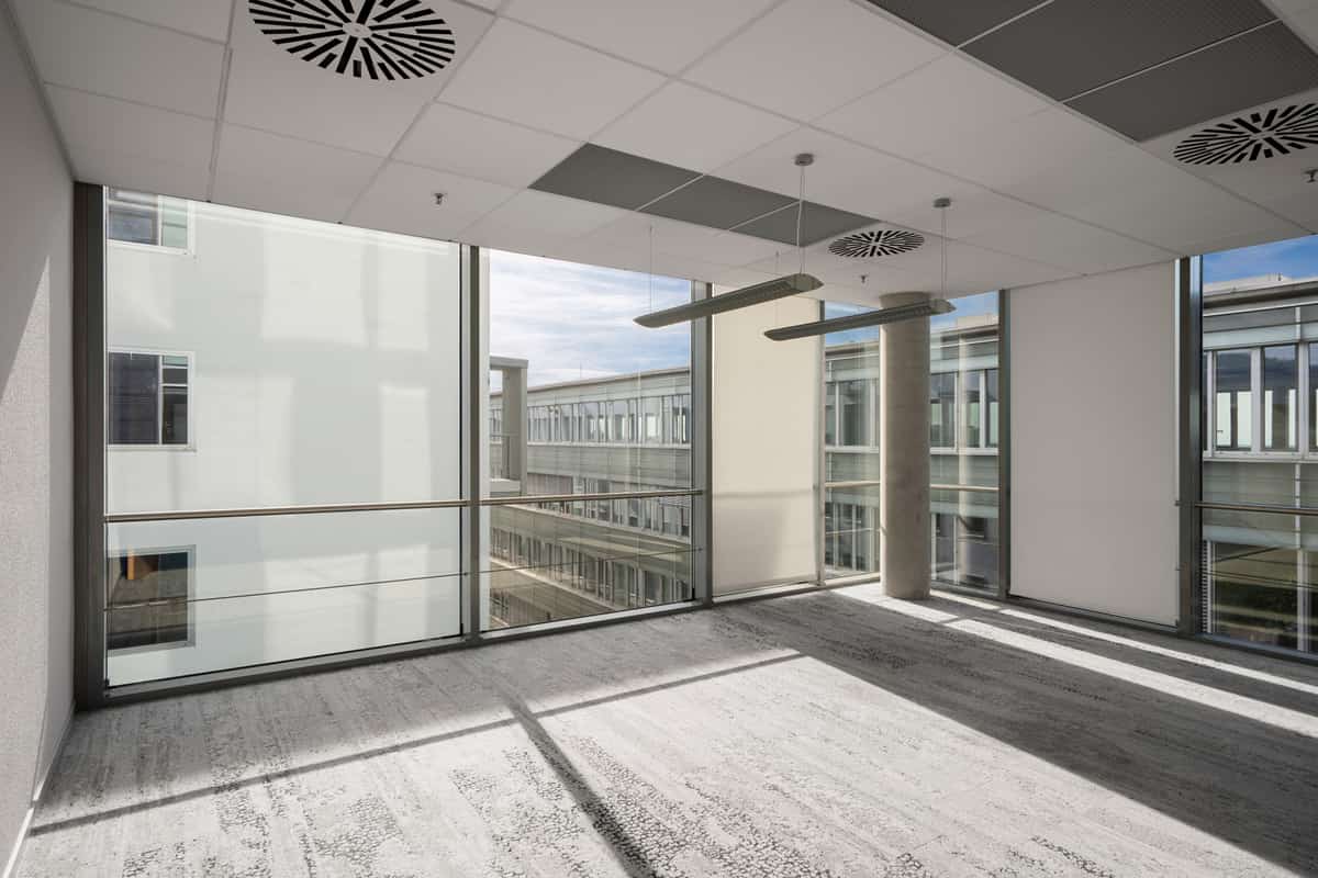 Leere Bürofläche mit Fensterfront und Blick auf angrenzende Gebäude