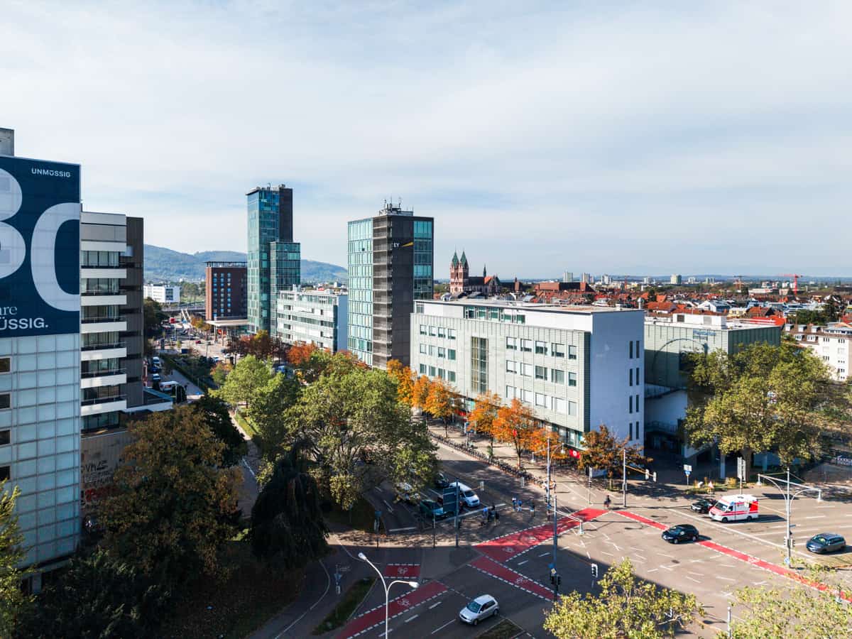 Luftaufnahme der Bahnhofszeile Freiburg mit Bürotürmen, Straßenkreuzung und Blick über die Stadt