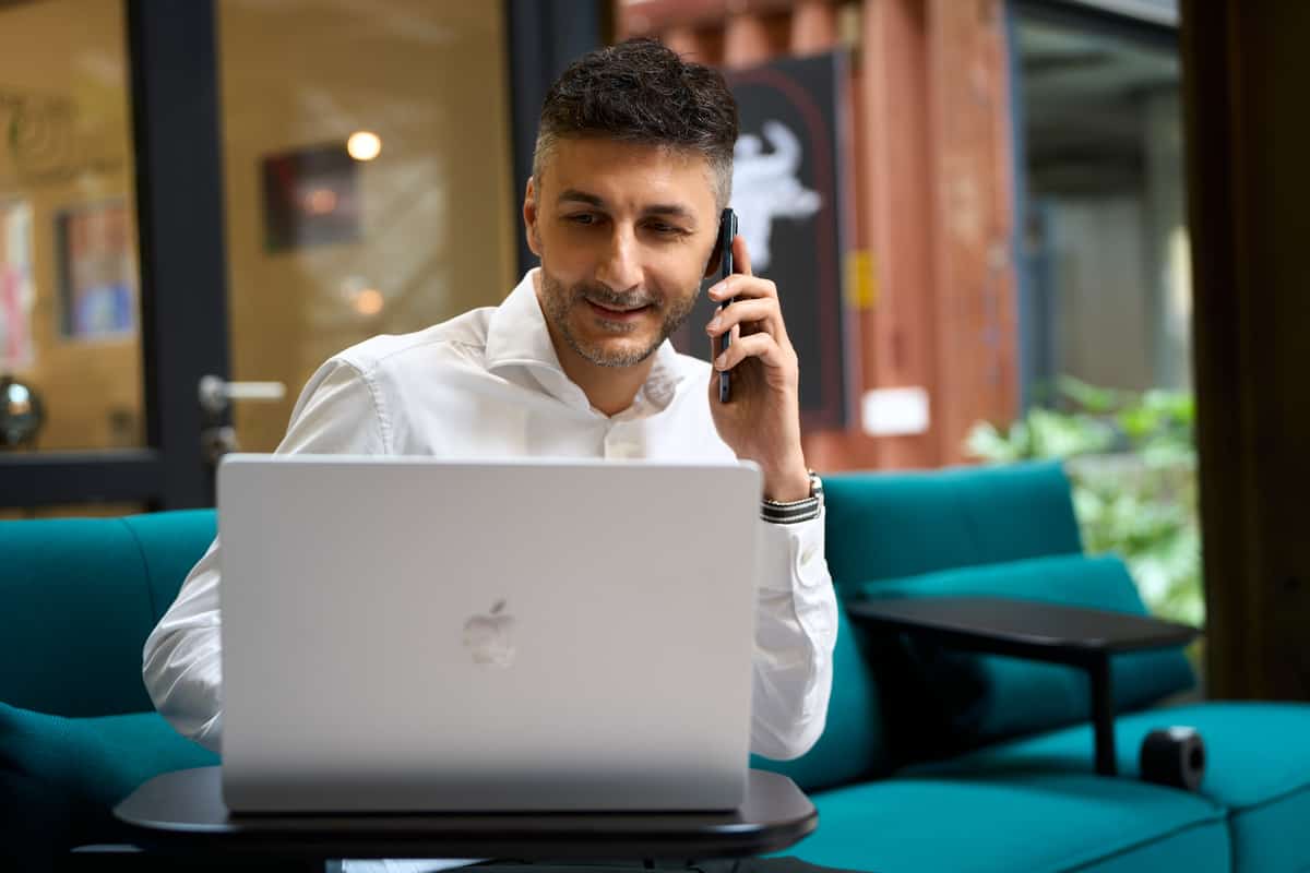 Giuseppe Conforti telefoniert am Laptop auf einem türkisen Sofa in der Lokhalle.