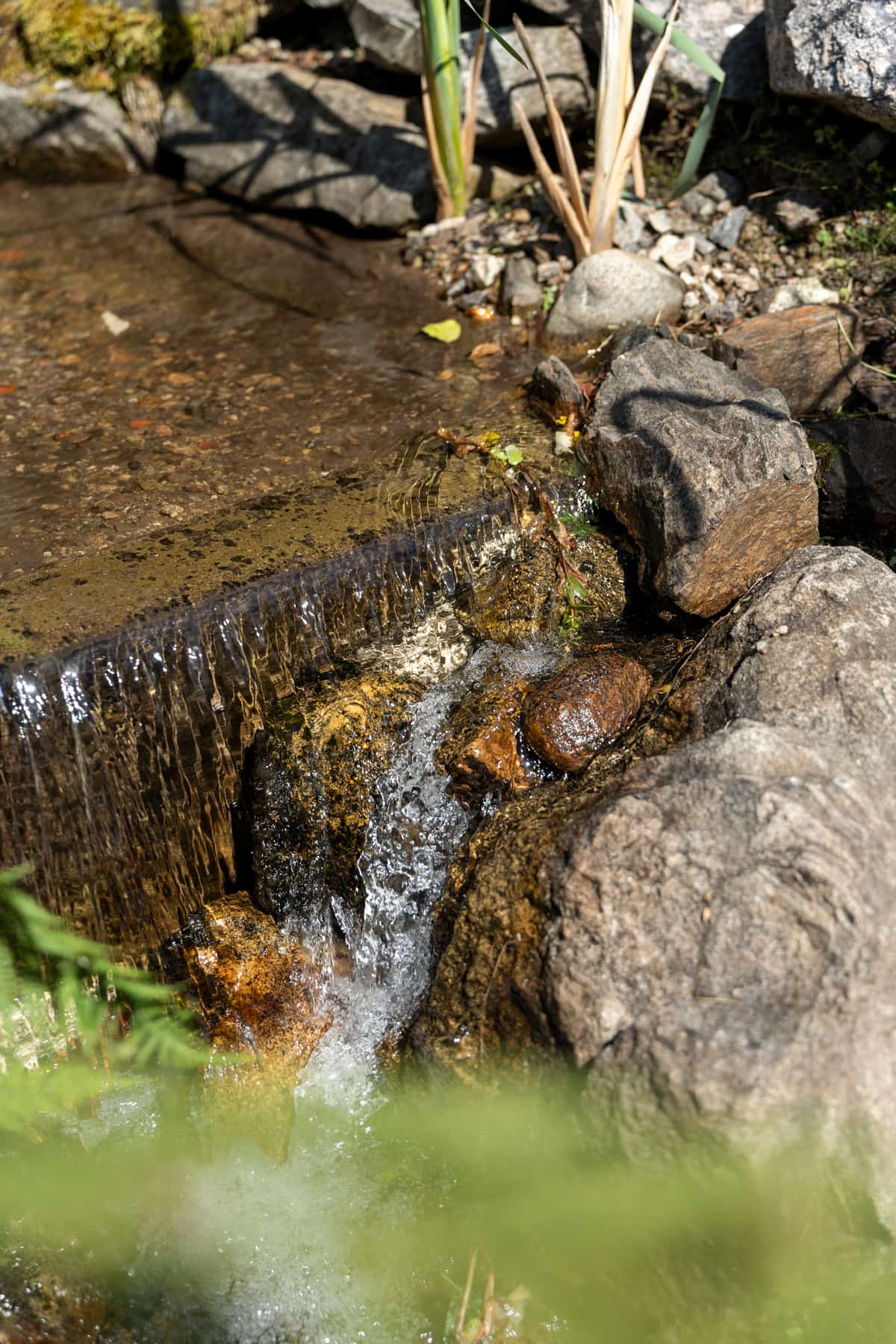 Eigener Brunnen mit Wasserlauf zwischen Steinen auf dem Grundstück