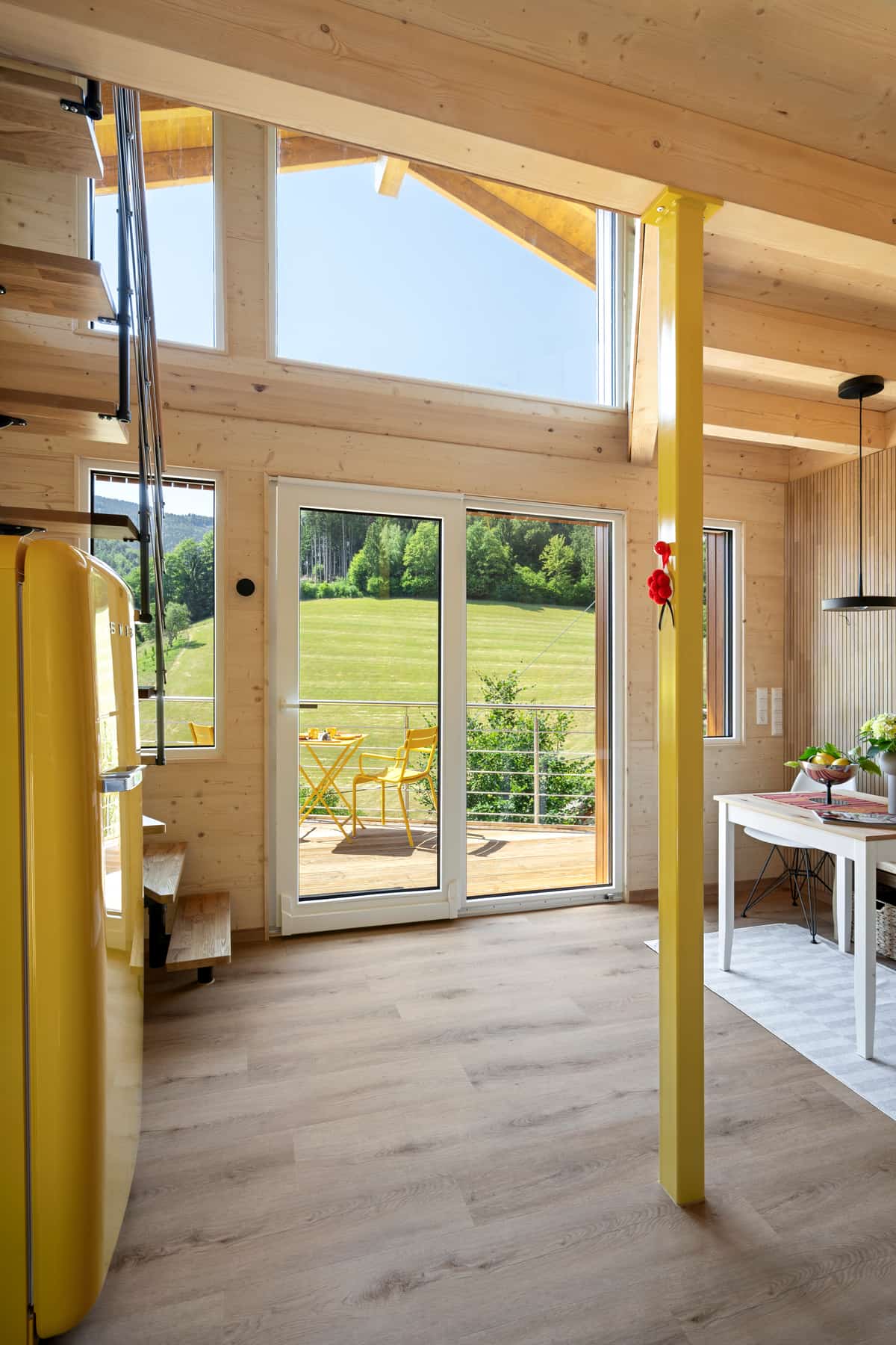 Offener Wohnbereich in Holzbauweise mit Holzdecke und gelbem Kühlschrank