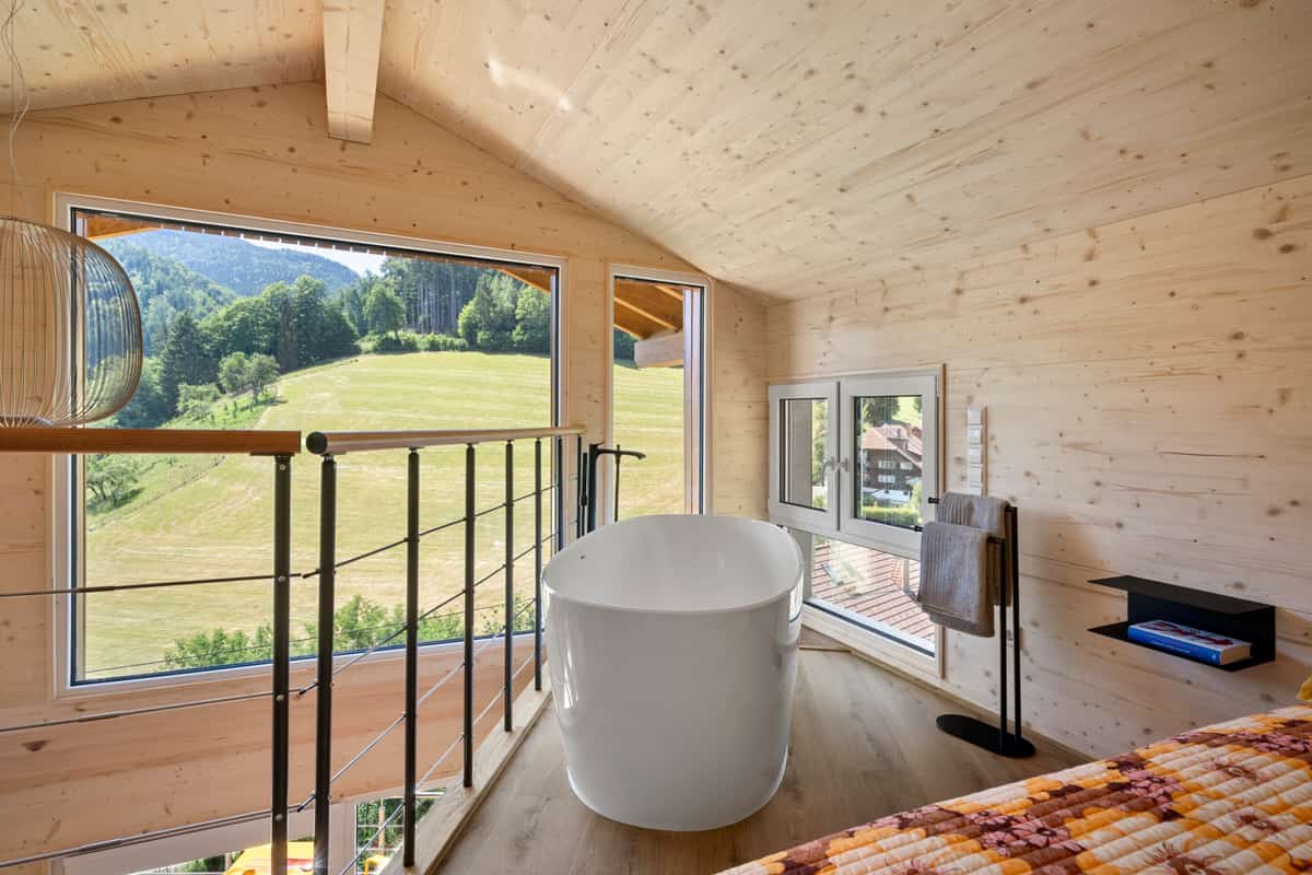 Freistehende Badewanne am Fenster mit Blick auf die Hanglandschaft