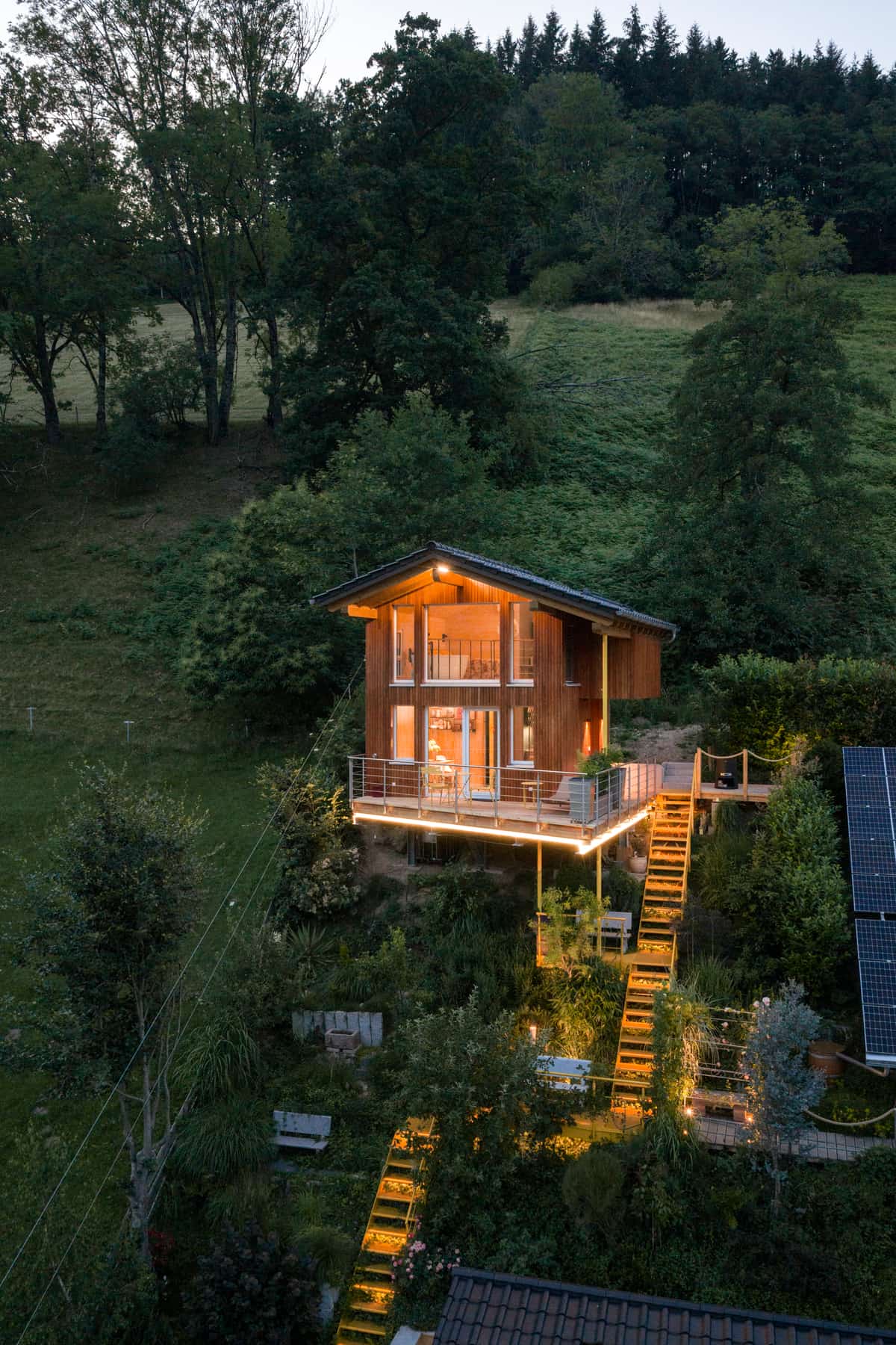 Ferienhaus im Holzbau bei Dämmerung, Luftaufnahme zur blauen Stunde