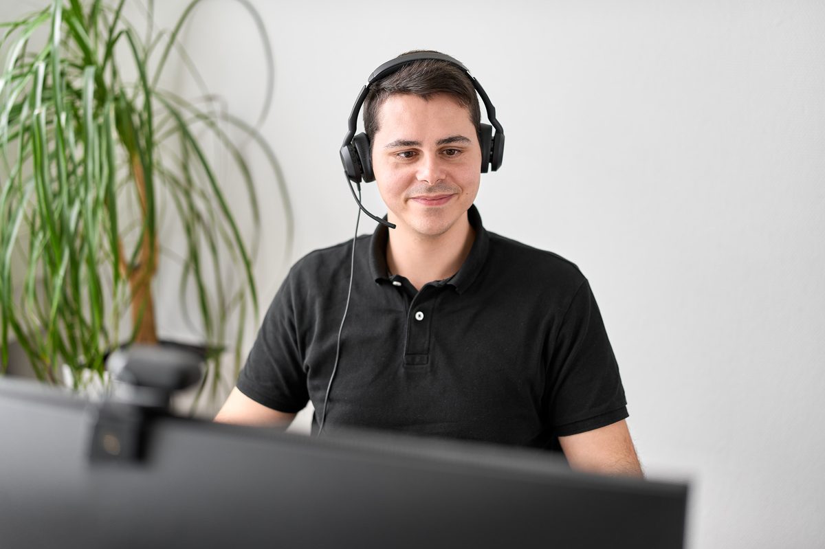 Hecht · Zwei Manager am Besprechungstisch, HECHT-Logo im Hintergrund