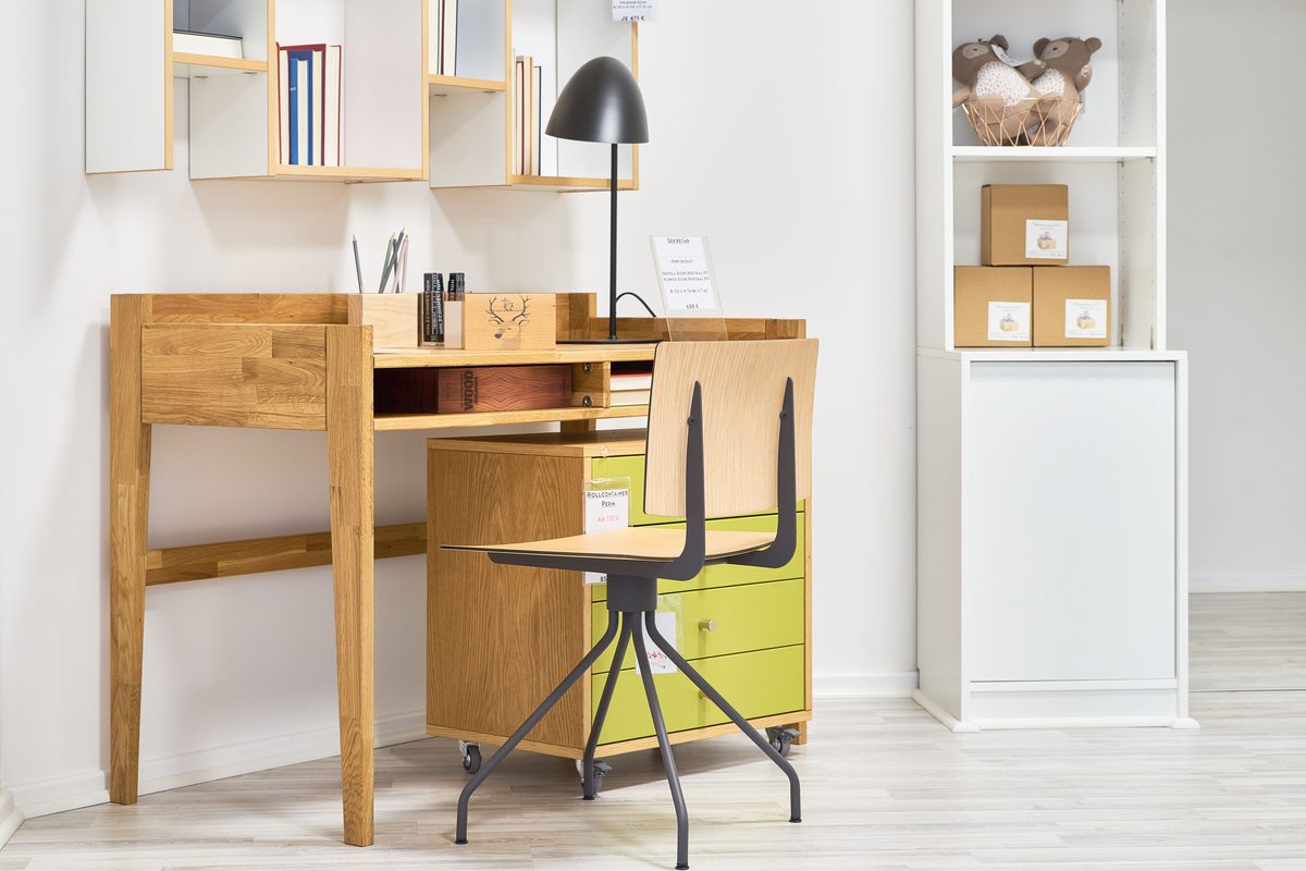 Holzconnection: Ein Holzschreibtisch mit Rollcontainer und Stuhl, umgeben von Regalen mit Büchern und Dekoration