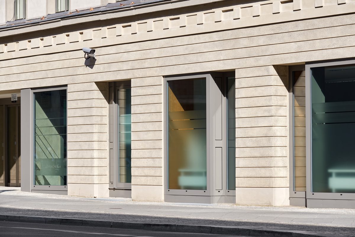 Fassade eines Gebäudes mit mehreren Fenstern und einer Überwachungskamera, die auf die Straße gerichtet ist.