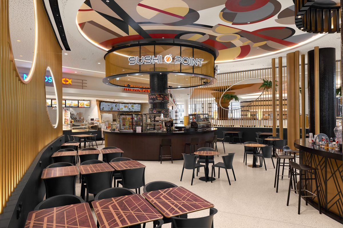 Ein Innenraum mit Tischen und Stühlen, einer Sushi-Bar und einer Decke mit geometrischen Mustern.