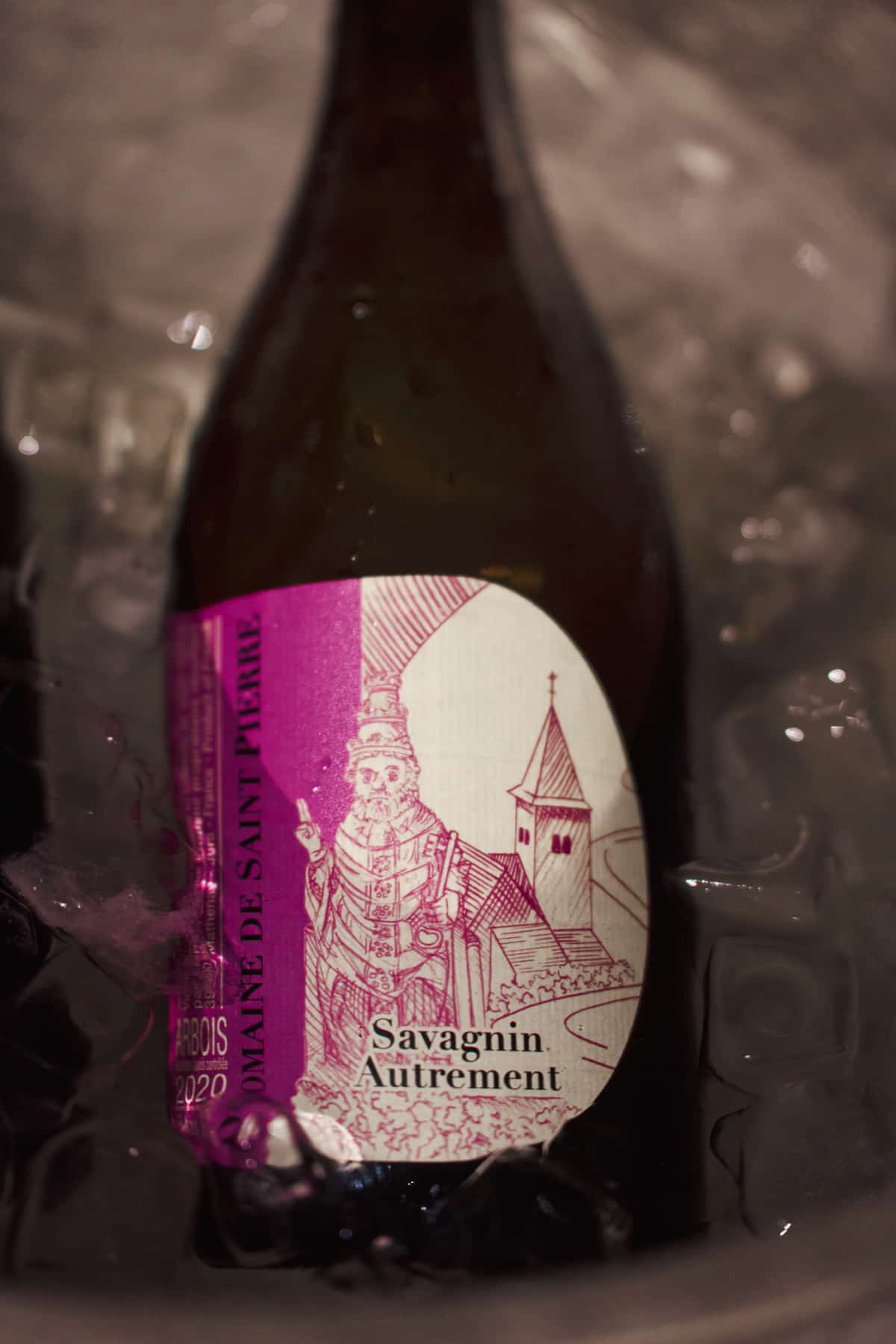 Nahaufnahme einer Weinflasche mit dem Etikett Domaine de Saint Pierre, Savagnin Autrement, Arbois 2020, stehend in einem Eiskübel.