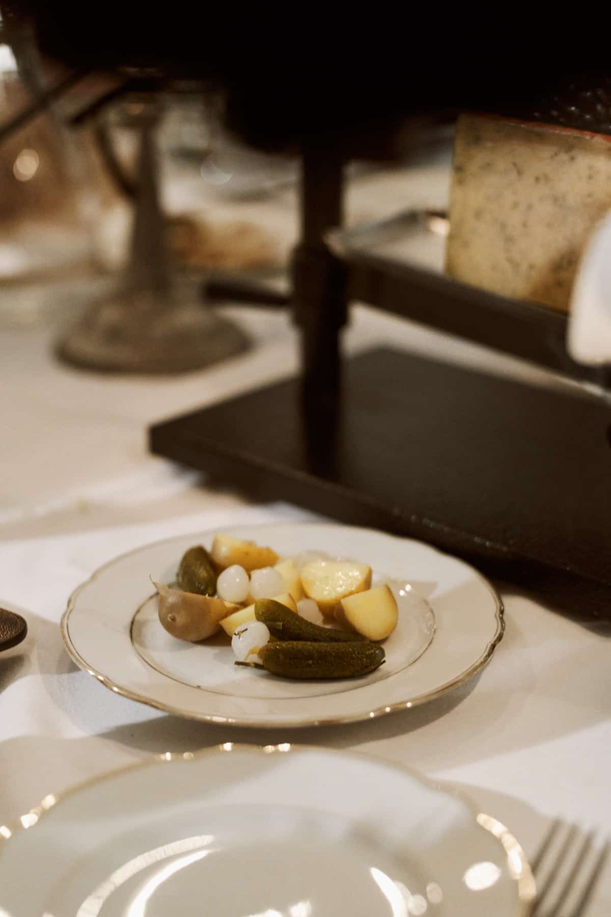 Teller mit sauren Gurken, Perlzwiebeln und kleinen gekochten Kartoffeln als klassische Raclette-Beilagen.