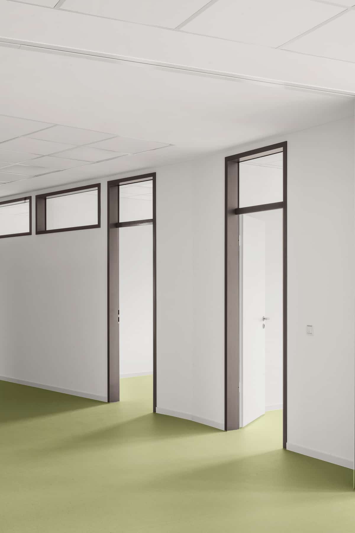 Hochformat Nahaufnahme eines Innenflurs mit mehreren Türen und dunkel gerahmten Türzargen entlang der Wand.