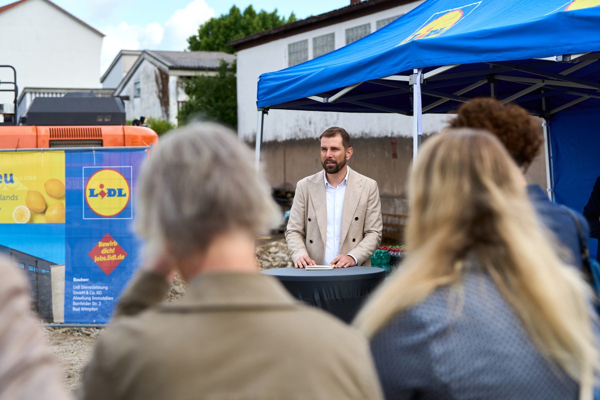 Ansprache vor Publikum am Lidl-Baustellenbanner