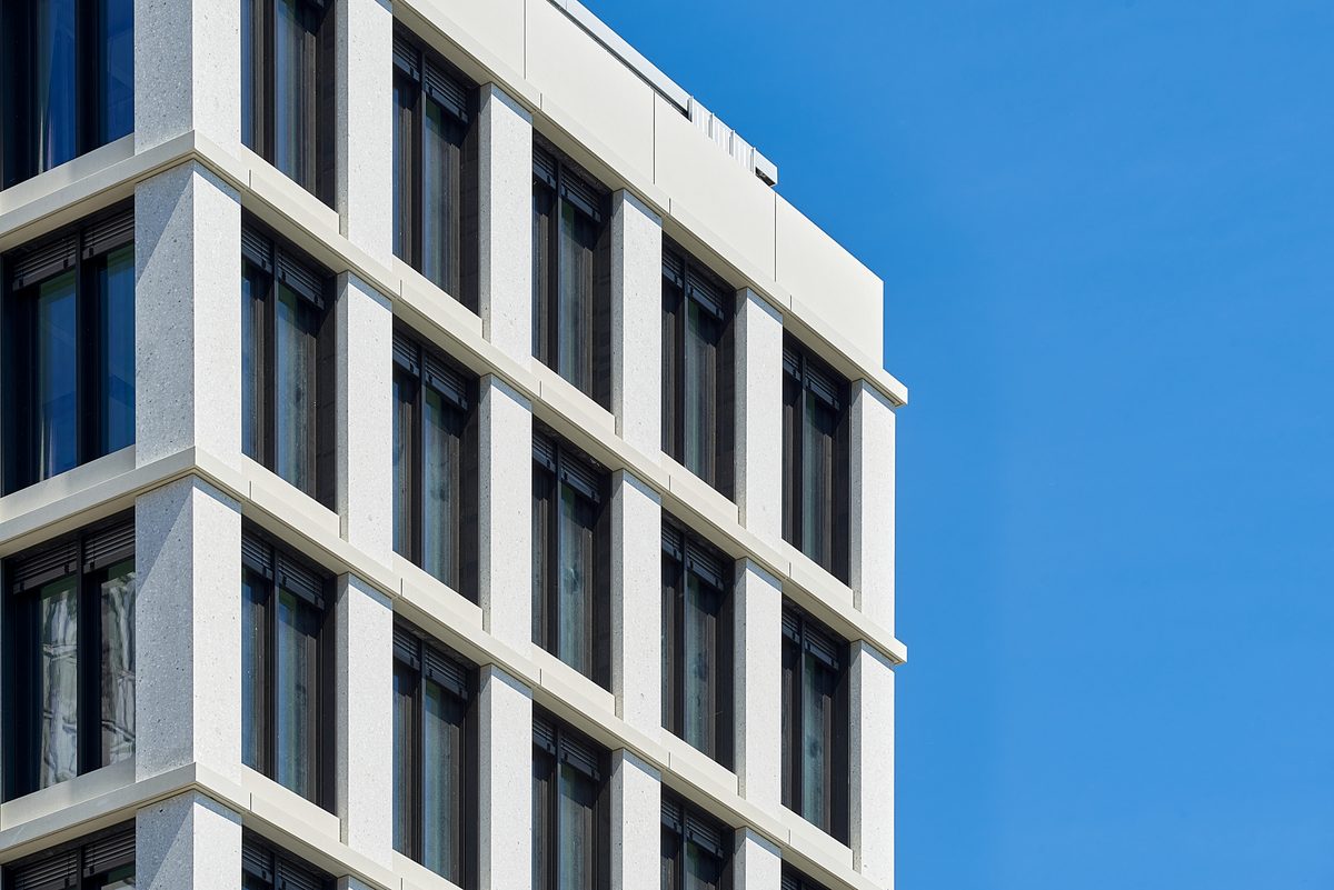 TRION · Architekturdetail Fassade, weiße Natursteinrahmung vor blauem Himmel